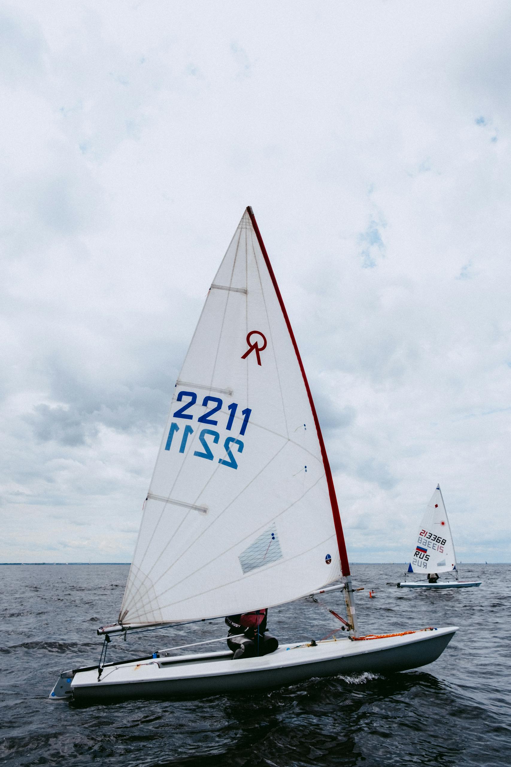 Exciting sailing regatta with vibrant sailboats racing across the open sea under a cloudy sky.